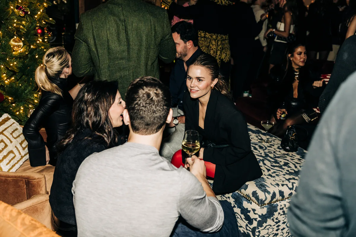 Guests talking over drinks in the lounge beside a lit tree