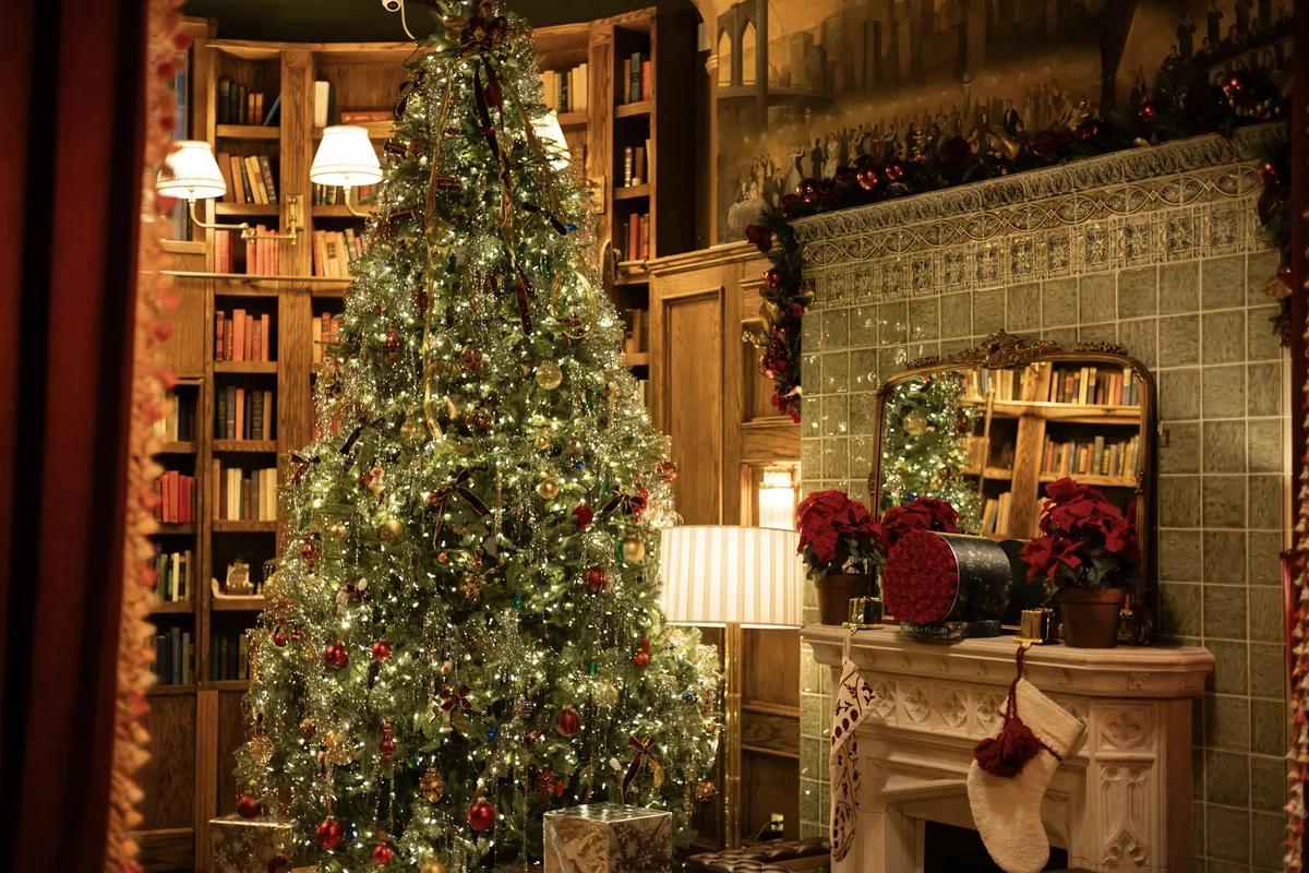Lit tree, bookshelves and a garlanded mantel